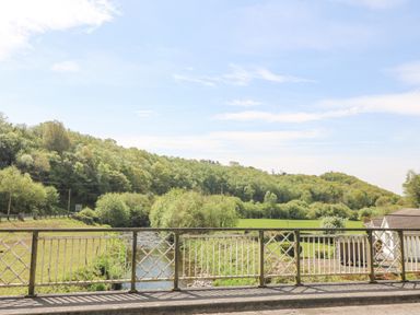 A view of a river and green trees from a bridge with a house roof visible at Coffey's in Ballymacarbry County Waterford