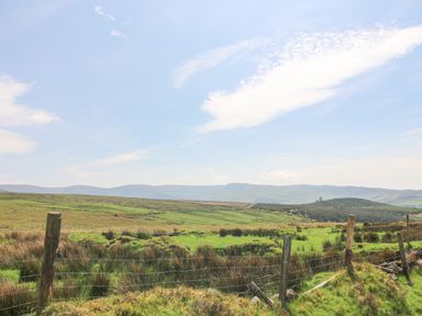 A rural landscape with green fields and fencing under a blue sky at Coffey's in Ballymacarbry County Waterford