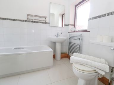 A bathroom with a bathtub sink toilet towels and a window at Kiama in Weymouth
