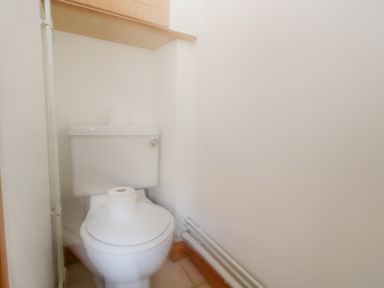 A small bathroom with a toilet and a roll of toilet paper on the seat at Kiama in Weymouth