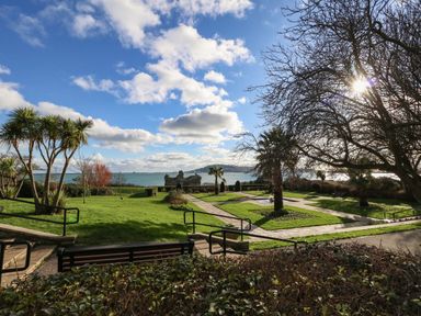 An outdoor garden with grass paths benches and trees overlooking the sea at Kiama in Weymouth