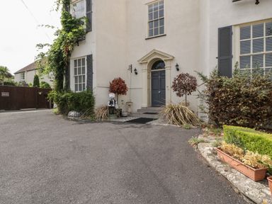 Front entrance of a house with a grey door plants and shrubs on either side at Alcombe House in Minehead