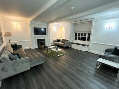 A living room with sofas a coffee table a wall-mounted TV and a window seat at Alcombe House Minehead