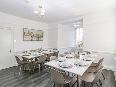 A dining room with two tables set with plates bowls and glasses and gray chairs at Alcombe House in Minehead