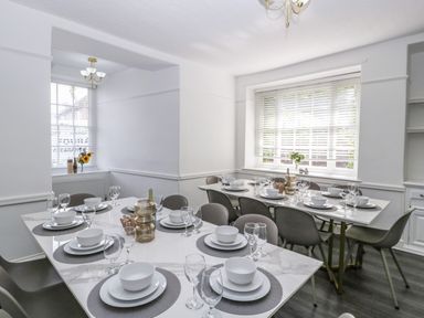 A dining room with two tables set with plates bowls wine glasses and chairs at Alcombe House Minehead