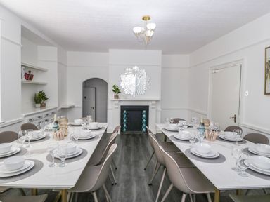 A dining room with two tables set with plates bowls and glasses a fireplace with a decorative mirror and chairs at Alcombe House in Minehead