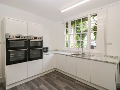 A kitchen with built in ovens a microwave a sink and a large window at Alcombe House in Minehead