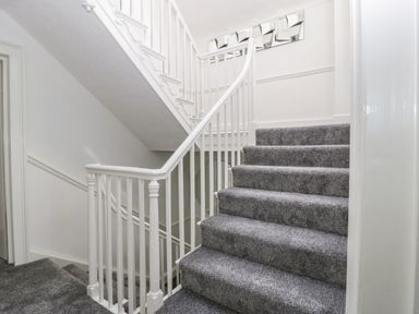 A carpeted staircase with white railings and a decorative mirror on the wall at Alcombe House in Minehead