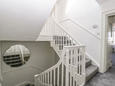 A staircase with grey carpet and white railing and an open door leading to a room at Alcombe House in Minehead