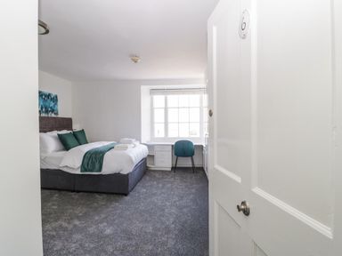 A bedroom with a bed a desk and chair by a window at Alcombe House in Minehead