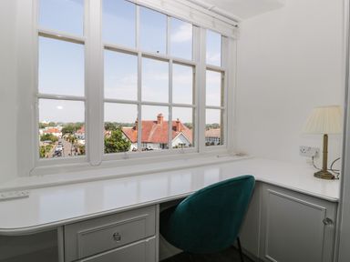 A white desk with drawers and a lamp by a window with a view of houses and a street at Alcombe House in Minehead
