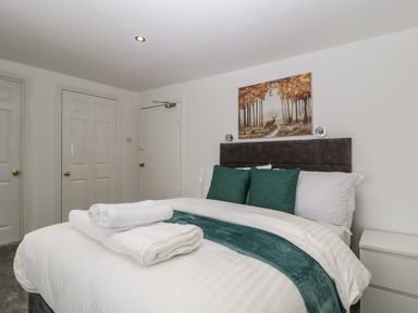A bedroom with a bed with green cushions white towels and a painting above at Alcombe House Minehead