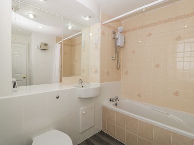 A bathroom with a bathtub shower toilet and sink at Alcombe House in Minehead