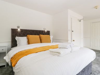 A bedroom with a bed with yellow pillows and blanket and white towels on it at Alcombe House in Minehead