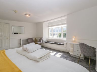 A bedroom with a bed towels table and chairs near a window at Alcombe House in Minehead