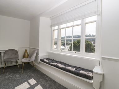 A room with a window seat with cushions two gray chairs and a decorative vase at Alcombe House in Minehead