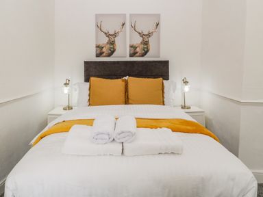 A bedroom with a bed with orange cushions and white towels on it at Alcombe House Minehead