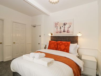 A bedroom with an orange throw and pillows on the bed at Alcombe House in Minehead