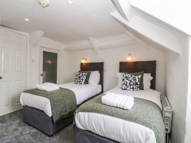 A bedroom with two single beds with green throws and pillows at Alcombe House in Minehead