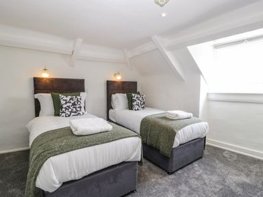 A bedroom with two single beds each with pillows and folded towels at Alcombe House Minehead