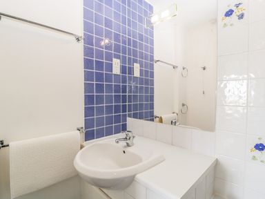 A bathroom sink with a faucet and a mirror above it with blue and white tiled walls at Alcombe House in Minehead