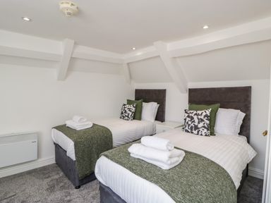 A bedroom with two single beds with green throws and pillows at Alcombe House in Minehead