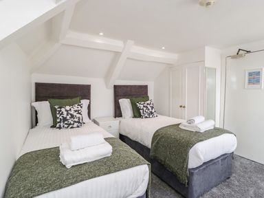 A bedroom with two single beds nightstand and folded towels on the beds at Alcombe House in Minehead