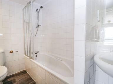 A bathroom with a bathtub shower toilet and sink at Alcombe House in Minehead