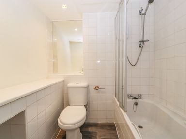 A bathroom with a toilet and a bathtub with a showerhead at Alcombe House in Minehead