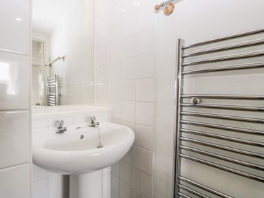 A bathroom sink with taps and a metal towel radiator at Alcombe House Minehead