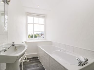 A bathroom with a sink a bathtub a window and a towel rack at Alcombe House in Minehead