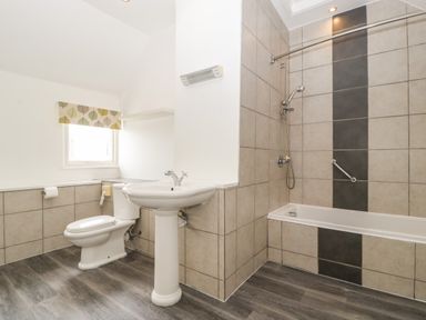 A bathroom with a toilet pedestal sink and bathtub with shower at Alcombe House Minehead