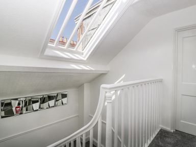 A stairwell with white railing skylight window and a mirrored wall decoration at Alcombe House Minehead