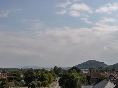 A landscape view with trees houses and hills under a cloudy sky at Alcombe House Minehead
