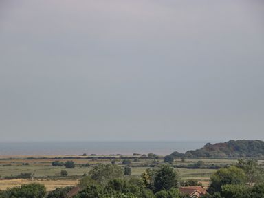 A landscape with fields trees and a body of water in the distance at Alcombe House in Minehead