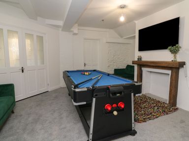 A game room with a pool table and two green sofas at Alcombe House in Minehead