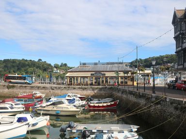 A marina with boats docked near a building and a bus on a road at The Mew in Dartmouth