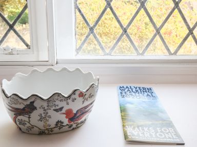 A decorative bowl with birds and a brochure on a windowsill at Gable Lodge in Malvern