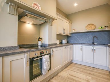A kitchen with white cabinets a countertop oven stovetop and a sink at Gable Lodge in Malvern