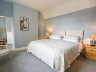 A bedroom with a double bed two bedside tables with lamps a chair and a painting on the wall at Gable Lodge Malvern