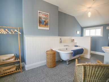 A bathroom with a freestanding bathtub a wicker basket and a wooden clothes rack at Gable Lodge in Malvern
