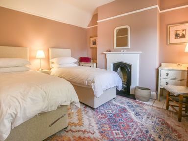 A bedroom with two single beds a fireplace rugs and bedside tables at Gable Lodge Malvern