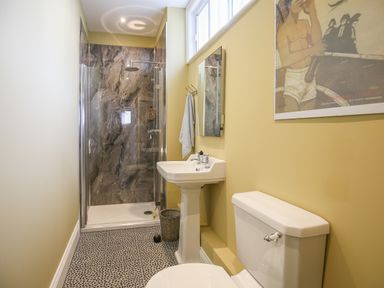 A bathroom with a toilet sink glass shower and a framed picture on the wall at Gable Lodge in Malvern