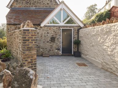 An exterior stone wall entrance with a black door numbered 2 and a paved driveway at Gable Lodge in Malvern