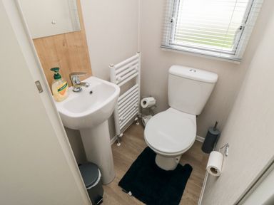 A small bathroom with a toilet sink mirror soap dispenser towel radiator and window at Pines 30 in Cayton