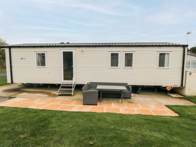 A mobile home with stairs leading to a door and outdoor seating on a paved area in front at Pines 30 in Cayton