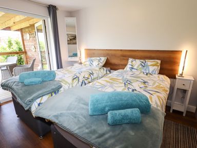A bedroom with two single beds with patterned bedding and blue towels at Meols Holiday Lodge in Meols