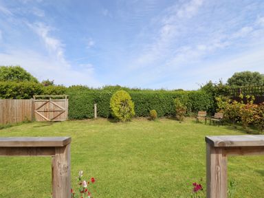 A backyard with grass lawn wooden fence wooden gate and two chairs at Meols Holiday Lodge in Meols