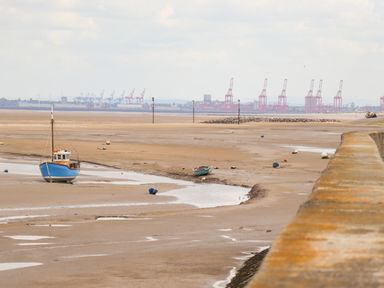 A beach with boats on the sand and cranes in the distance at Meols Holiday Lodge in Meols