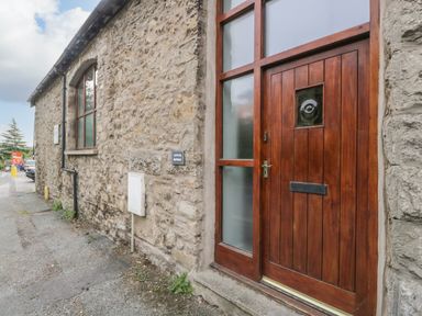 A stone exterior wall with a wooden door and window at Coach House in Arnside